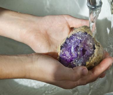 child washing a shiny amethyst stone
